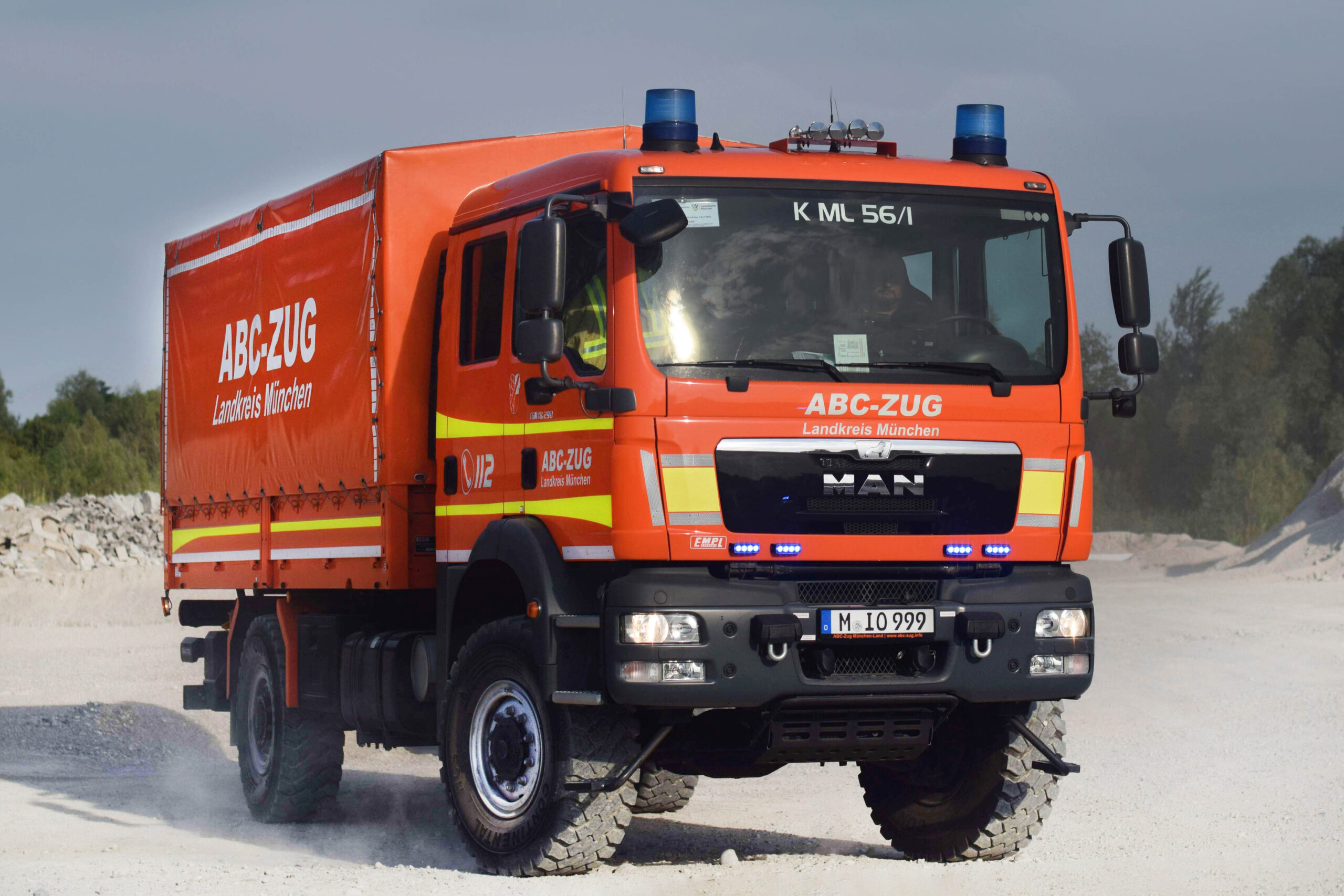 Bild des Versorgungs-Lkw. Ein oranger Lkw, welcher auf einem staubigen Untergrund fährt.