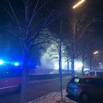 Eine Rauchwolke steigt aus einer Tiefgarageneinfahrt auf. Davor ein Feuerwehrfahrzeug mit aktivem Blaulicht.